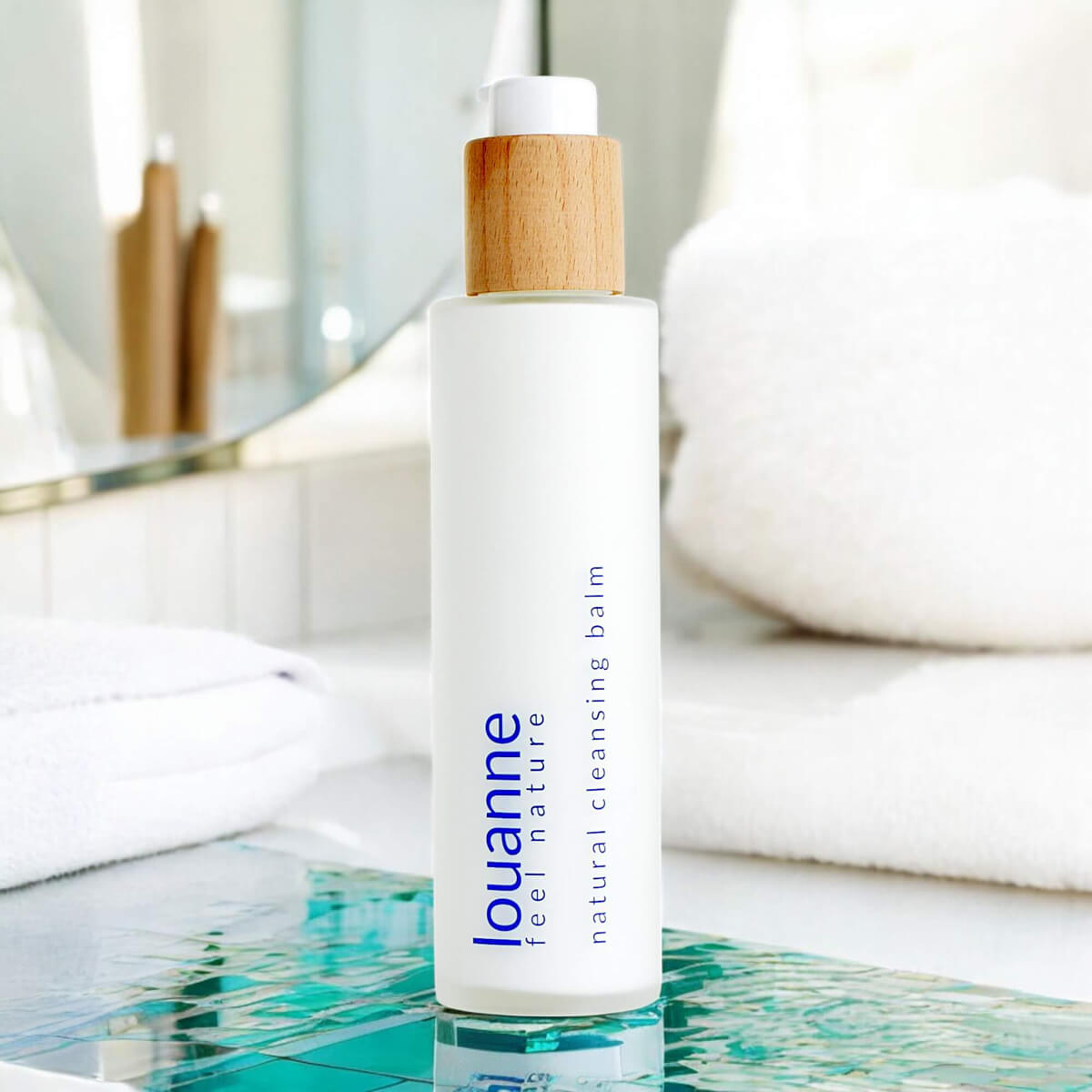 Louanne - palmölfreier Natural Cleansing Balm in Badezimmer-Setting mit Spiegel und weißen Handtüchern – stilvolle Naturkosmetik mit elegantem Design