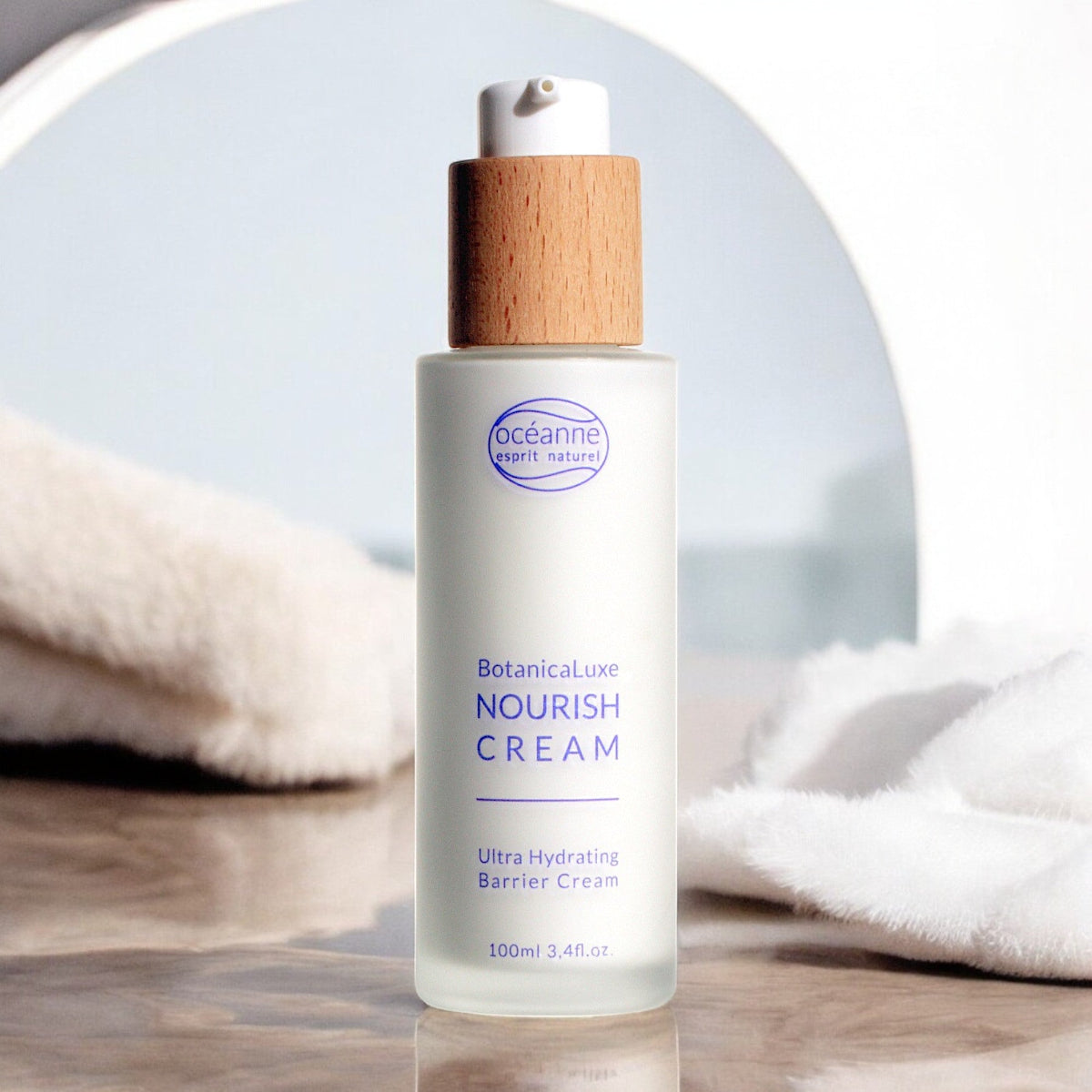 Flakon der palmölfreien Nourish Cream von Esprit Naturel mit Holzverschluss, stehend auf einem Marmoruntergrund vor einem Spiegel, umgeben von weichen weißen Tüchern – luxuriöses Naturkosmetik-Design.