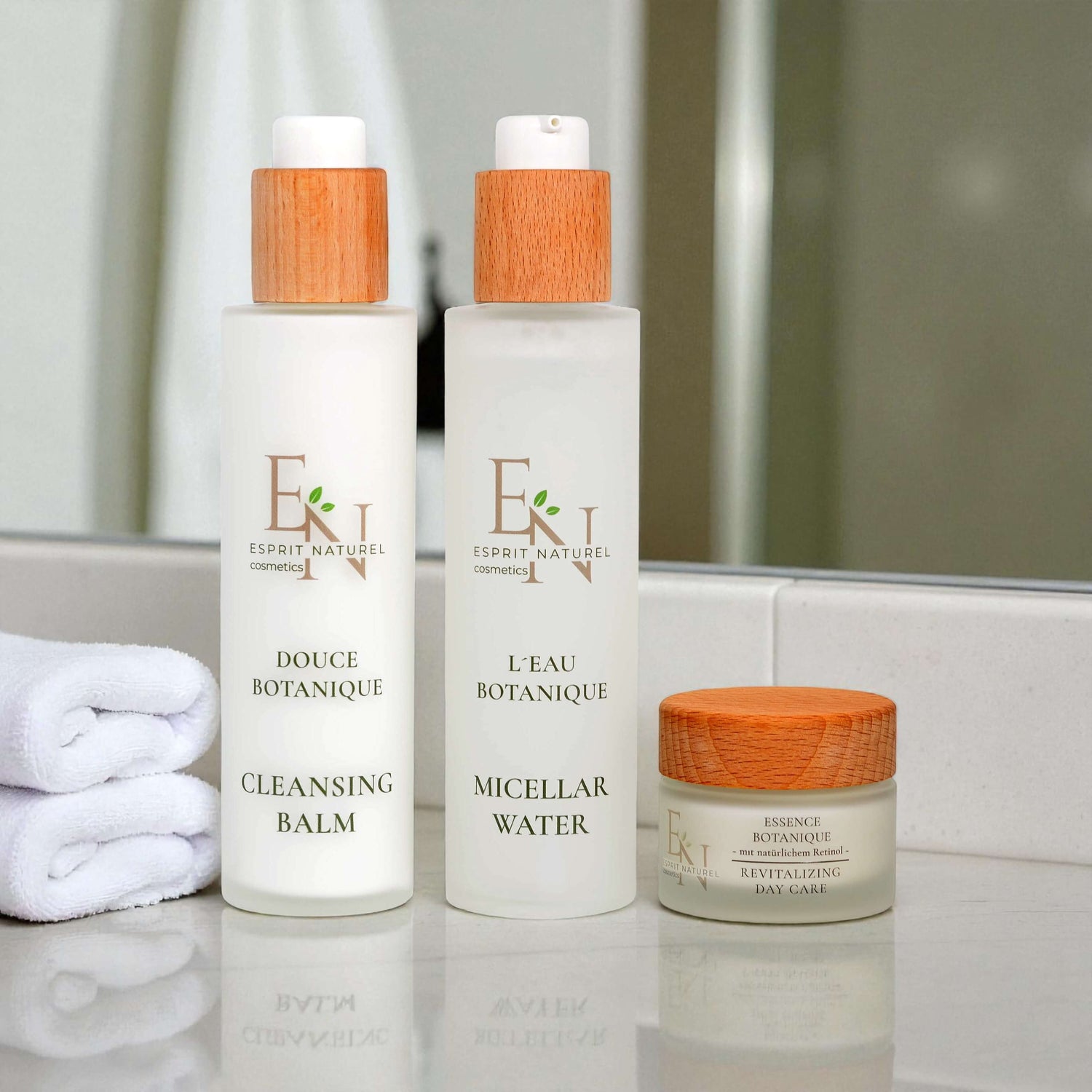 Esprit Naturel Naturkosmetik-Set mit Mizellenwasser, Reinigungsbalm und Tagescreme auf Marmor-Podest vor hellblauem Hintergrund – vegane, nachhaltige Hautpflege